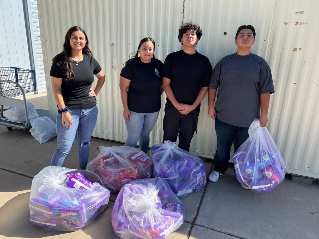 A mother with her adult children donating five bags of diapers to Hope Women's Center.